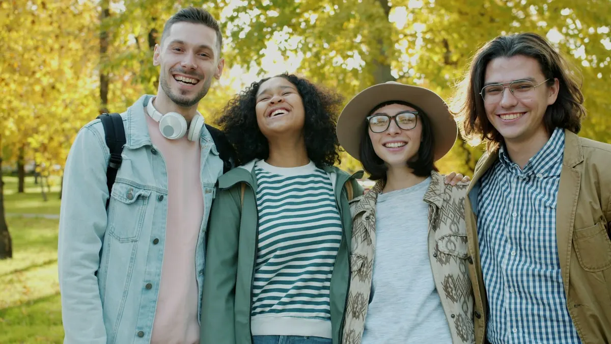 Four friends standing together in a park in autumn
