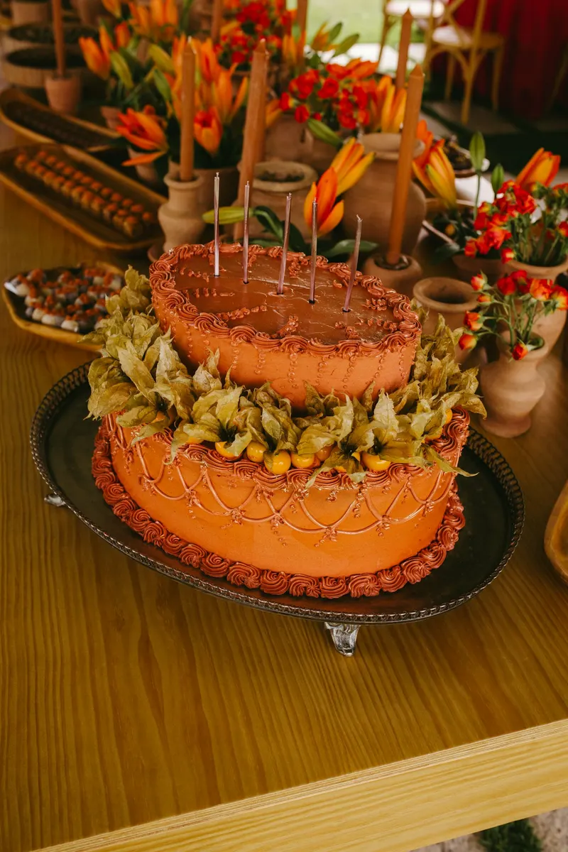 A decorated cake on a party table with orange flowers